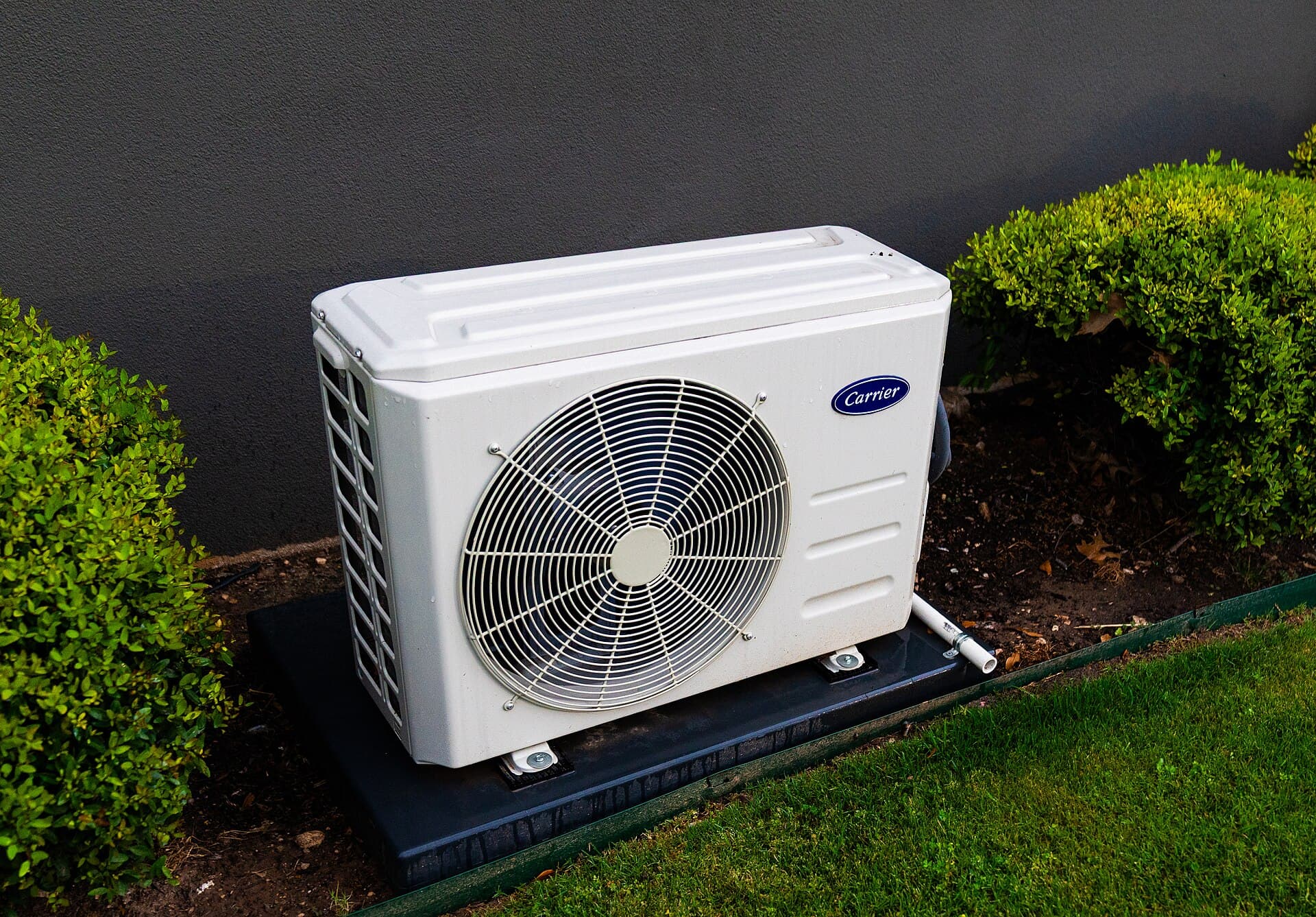 Split-system outdoor unit beside a dark rendered wall